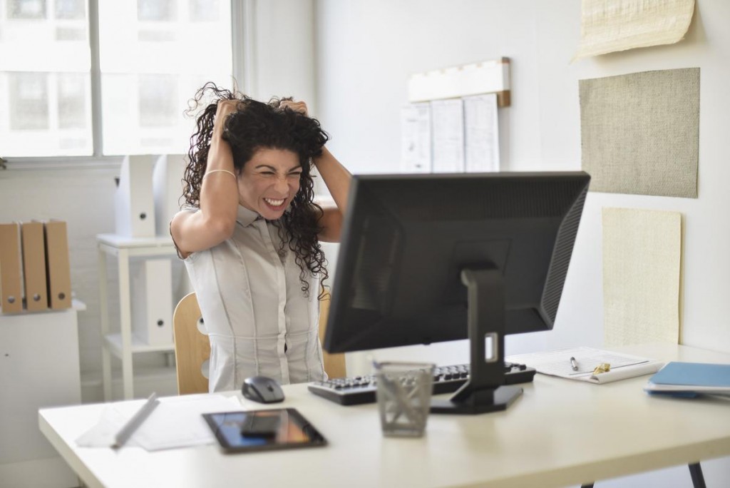 Mixed race businesswoman frustrated at computer at desk in office